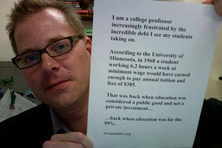 Prof. David Davies holding a sign; caption below